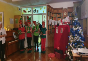 Rodzice przebrani za elfy wystawiają dla dzieci przedstawienie z okazji mikołajek.